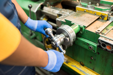 Close-up of unrecognizable machine operator turning handle of machine while adjusting metal part in...