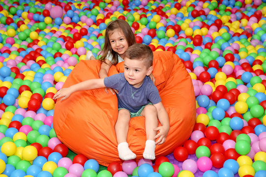 Cute children playing among plastic balls