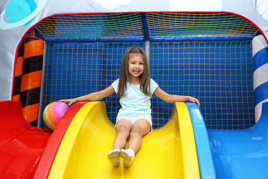Little girl riding on slide in entertainment center