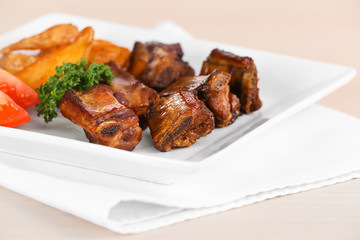 Plate with delicious grilled ribs on table, closeup