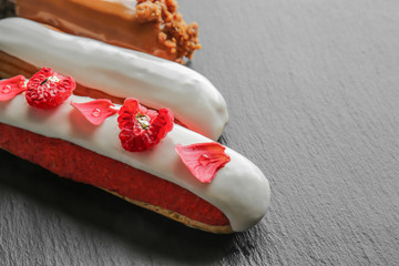 Various tasty eclairs on dark background