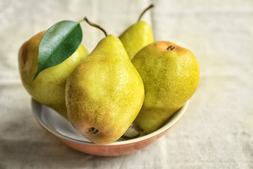 Delicious ripe pears in bowl on table