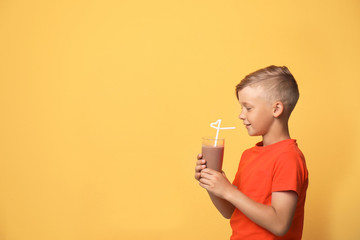 Little boy with glass of milk shake on color background