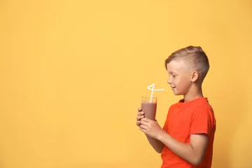Fototapete Milchshake Little boy with glass of milk shake on color background