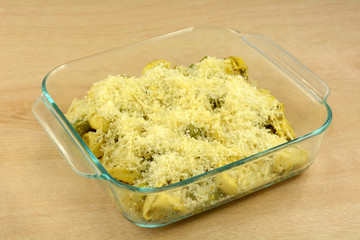 Preparation of cheese tortellini and asparagus and shredded cheese casserole in glass baking dish in advance for quick weekday dinners