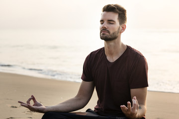 Man practicing yoga on the beach