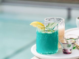 Tradition Summer bubble drink with lime mint and lemon slice against blur swimming pool background, cool green blue soft drink with copy space for text.
