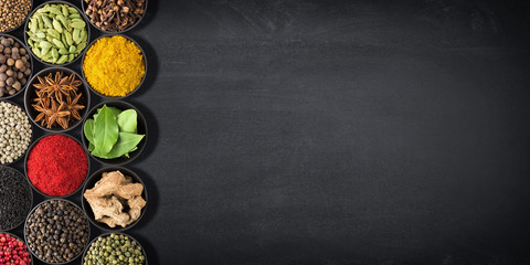 spices and herbs for cooking. seasonings on  black table with space for  recipe.