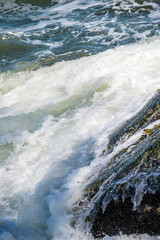 wave pounding the shore rocks under the sun