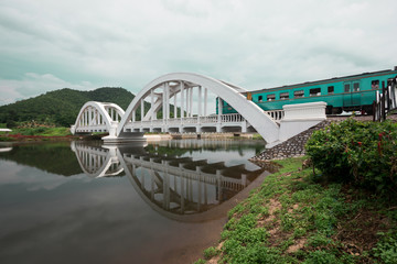 Fototapeta premium The train is crossing the white bridge with beautiful mountain view