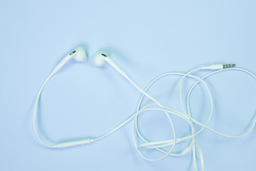 Obraz premium White Earphones or ear buds small talk on sweet blue colour pastel paper, top view, texture and background. music listening concept.