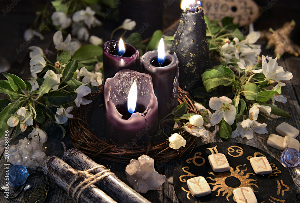 Wall mural Black candles with runes, zodiac circle and spring flowers. Occult, esoteric and divination still life. Halloween background with vintage objects and magic ritual 