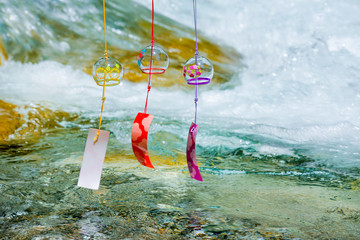 Japanese wind chimes with clean stream on the mountain river in the background.