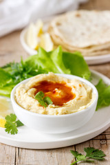 Hummus with olive oil and paprika, served with pita, lemon and lettuce leaves.