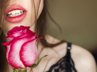 Close-up shot of sexy woman lips with red lipstick and beautiful red rose.