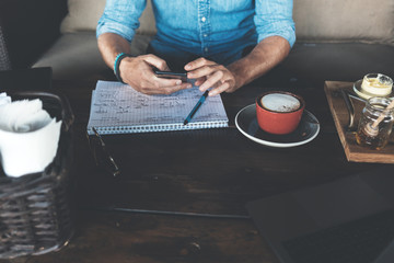 Entrepreneur working on his project at street cafe, using mobile phone close-up, breakfast time