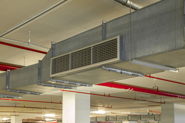 Industrial air duct ventilation equipment and pipe systems installed on industrial building ceiling.