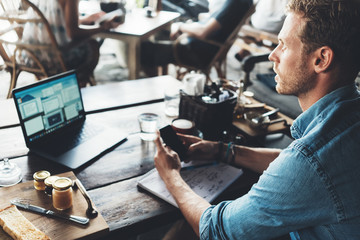Entrepreneur working on his project at street cafe, using mobile phone