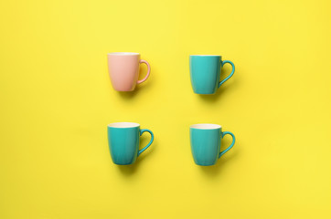 Pattern from blue cups over yellow background. Birthday party celebration, baby shower concept. Punchy pastel colors. Minimalist style design