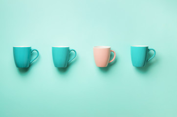 Pattern from blue and pink cups over turquoise background. Birthday party celebration, baby shower concept. Punchy pastel colors. Minimalist style design