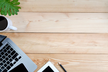 Workspace with laptop, tablet, smartphone and coffee cup on wooden desk.