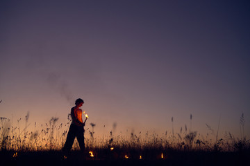 A man with a torch at sunset. Fire show and a lot of the bright sparks in the night