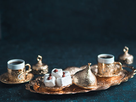 Turkish coffee with delight and traditional copper serving set on dark background. Assorted traditional turkish dilight or lokum and turkish coffee in metal traditional cups.Copy space.Selective focus