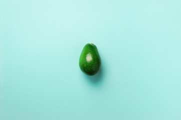 Green avocado on blue background. Top view. Pop art design, creative summer food concept. Minimal flat lay style.