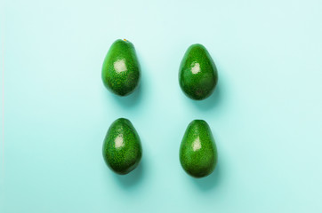Green avocado pattern on blue background. Top view. Pop art design, creative summer food concept. Organic avocadoes in minimal flat lay style.