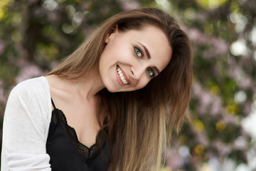 Portrait of a woman laughing with a perfect teeth on a warmth background. Woman smiling with perfect smile and white teeth in a park and looking at camera