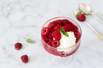 Strawberry Sunday with raspberries, decorated with mint leaves and served in a classic old glass goblet.