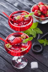 strawberry cocktail with ice and fresh mint on a black wooden table