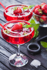 strawberry cocktail with ice and fresh mint on a black wooden table