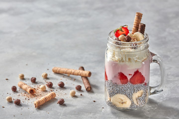 Mason jar with yogurt, berries and chia pudding on concrete background with cookies