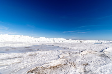 frozen lake covered with stack of ice floes and blue sky