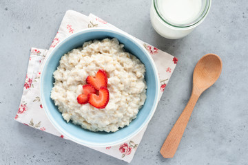 Oatmeal porridge with strawberries top view. Porridge oats in blue bowl. Top view of healthy breakfast
