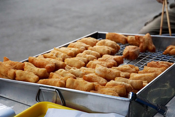 Chinese dough  in the stainless steel tray for sell in morning market of Thailand.Blured street background.