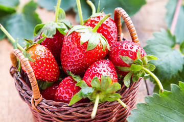 Fresh red strawberries are in a wooden basket