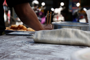 Fototapeta premium Preparation deep fried dough wood desk with flour and blurred hand man cooking background.