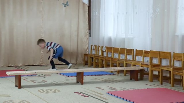 A good athlete trains a somersault on tatami and a jump through the bench