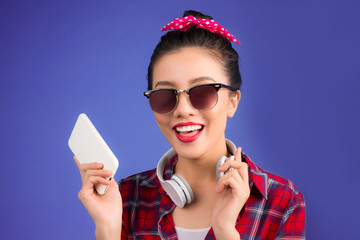 Happy young asian woman using smartphone standing over blue.