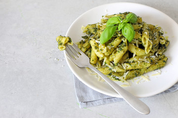 Pesto pasta. Pasta Penne in a white plate on gray background.