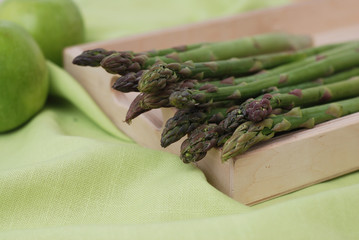 Asparagus Isolated on Wooden Board and Green Textile Background. Healthy Food Concept. Copy space.