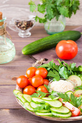 Fresh slices of cucumbers, tomatoes, sesame seeds in a bowl and parsley leaves on a plate on a wooden table. Oil and seasoning for cooking vegetable salad