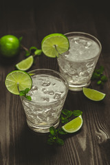 Fresh lime cocktail with ice cubes on wooden background