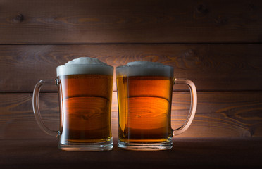 Two glasses of golden beer on wooden background