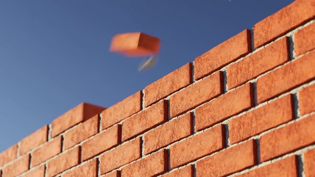 The clay brick wall being build at clear blue sky background. Loopable
