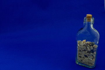 A bottle of sands and shells on the blue background