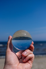 Fototapeta na wymiar chrystal ball on a mans palm on the beach