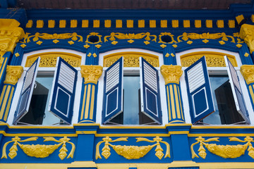 Beautiful colorful facade with open window shutters. Blue and yellow colors  style in architecture. Design of building exterior in Arab District of Singapore.